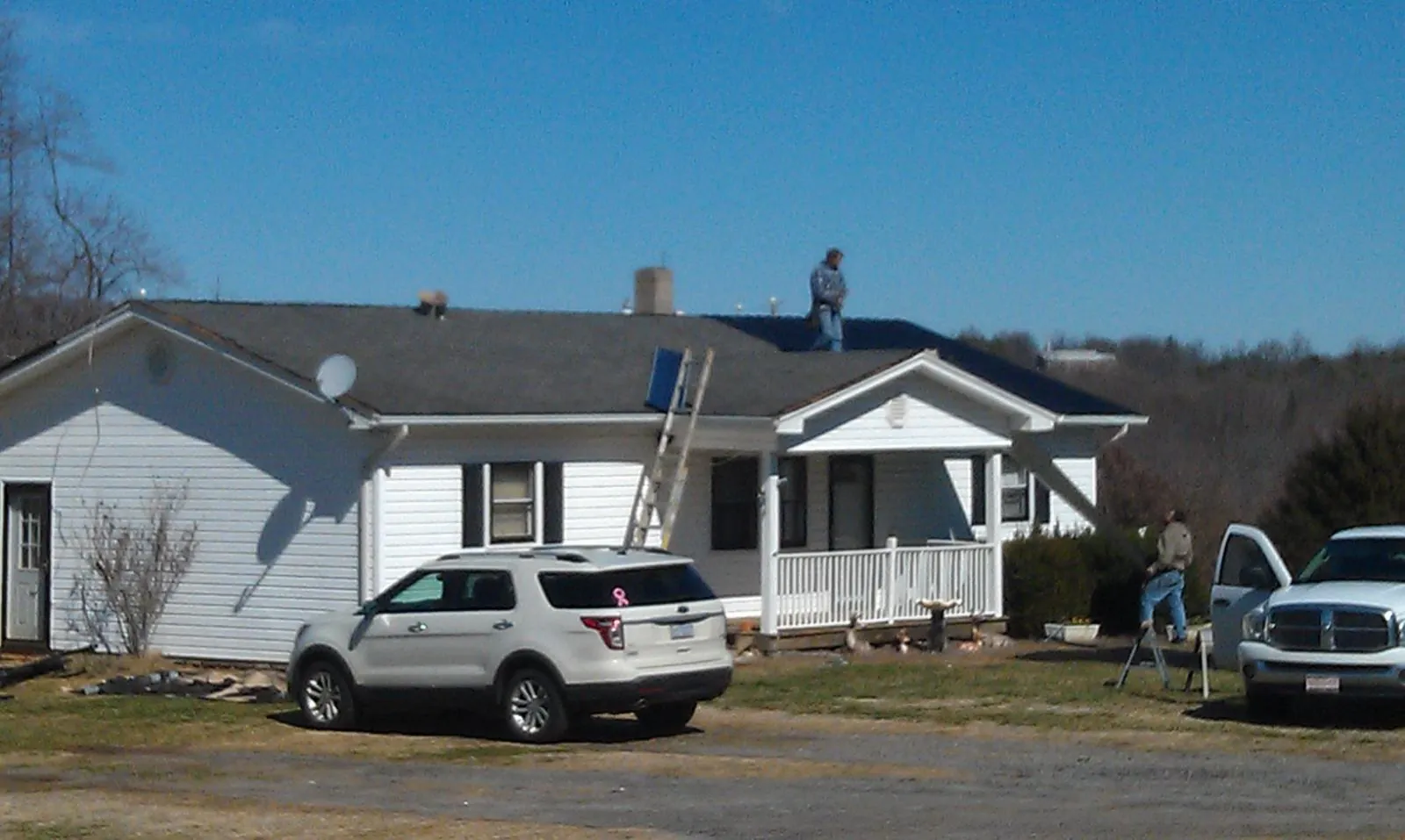 Roofers stripping shingles from a white ranch house roof in Ontario
