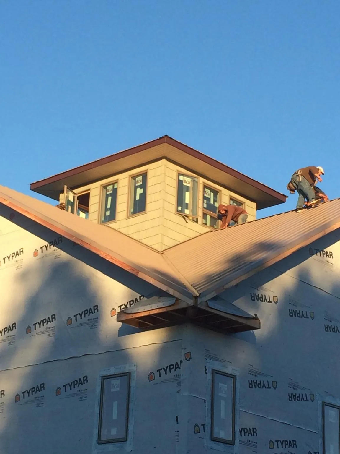 Roofers working around a rooftop cupola on a new metal roof at sunset — Roof Waterproofing in Ontario by Roofing Brothers